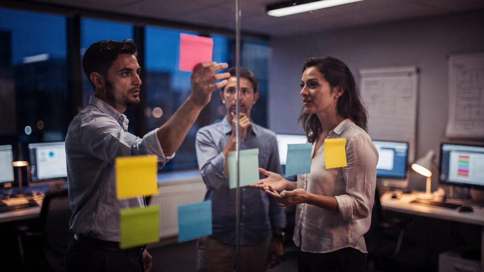A team arranging sticky notes on a glass wall while planning an MVP