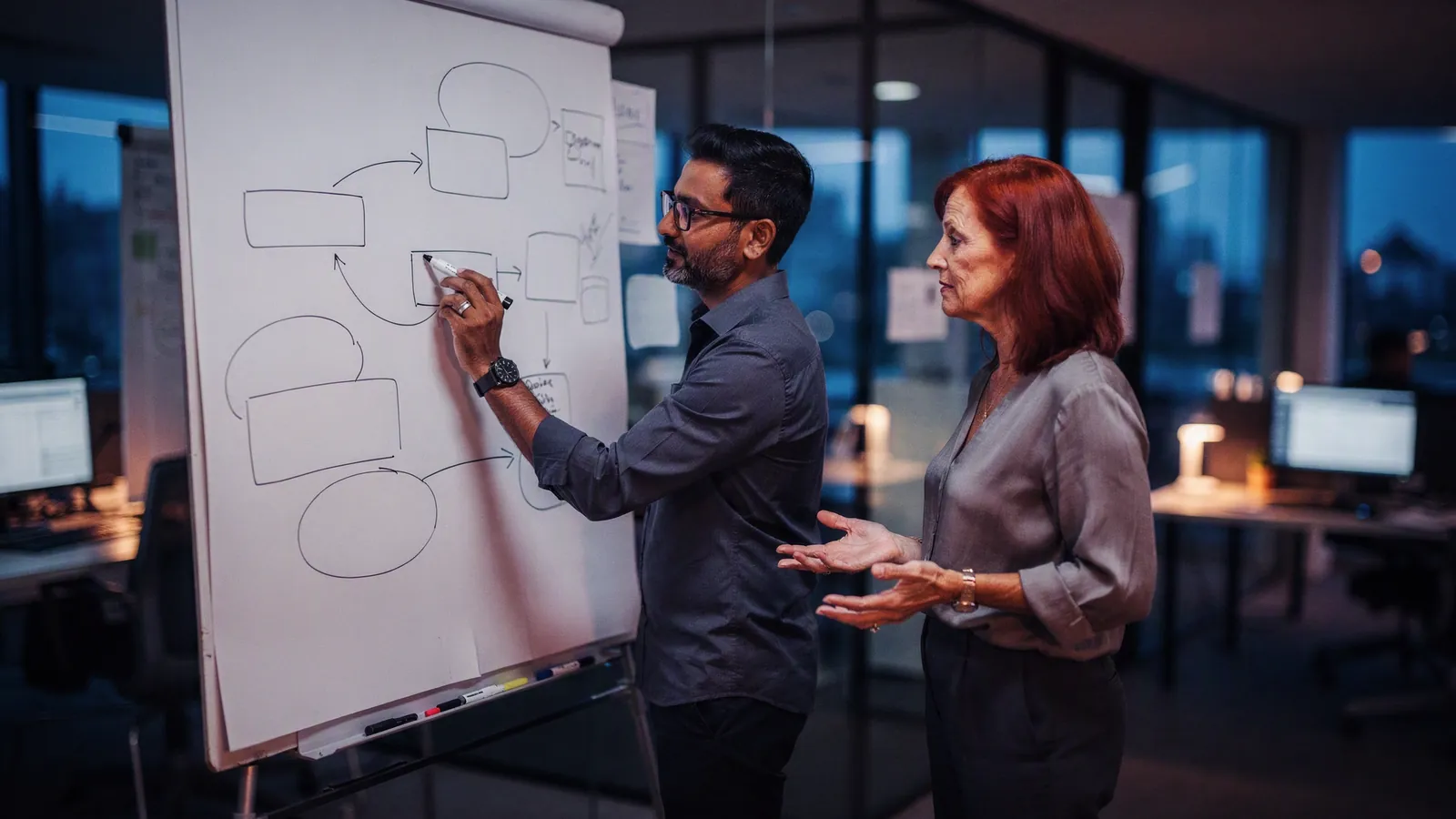 Two people sketching a system architecture on a whiteboard